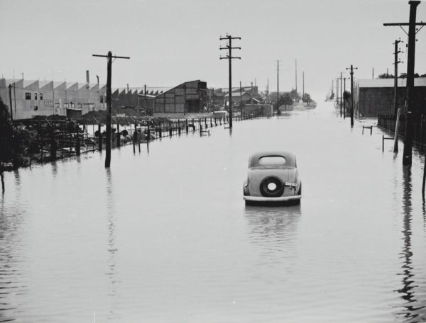 Car abandoned in the middle of a flooded thoroughfare.