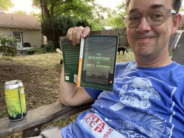 The author, showing off his new tshirt, drinking a beer, and reading "The Haunting of Hill House"