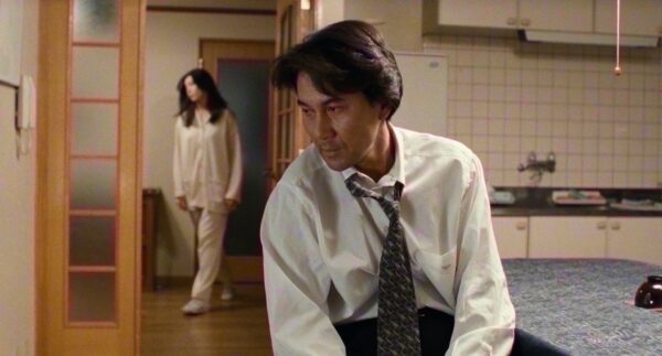 Detective Takabe at home, his wife having turned back on the dryer he'd just turned off, from the 1997 Kiyoshi Kurasawa film "Cure"