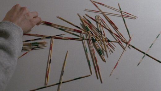 Still from the 1994 Michael Haneke film "71 Fragments of a Chronology of Chance" in which two boys play pick up sticks, a game of chance and skill