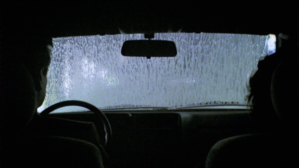 Still from the 1989 Michael Haneke film The Seventh Continent in which the family sits in the car going through an automatic car wash