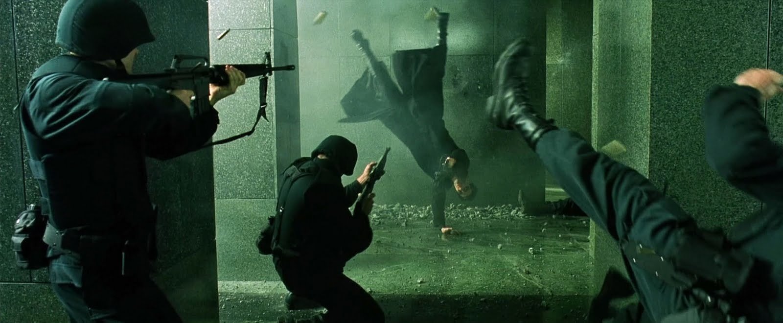 Still from the 1999 film The Matrix in which Neo and Trinity attack the building where Morpheus is being held. Here the idiotic gunplay has begun.